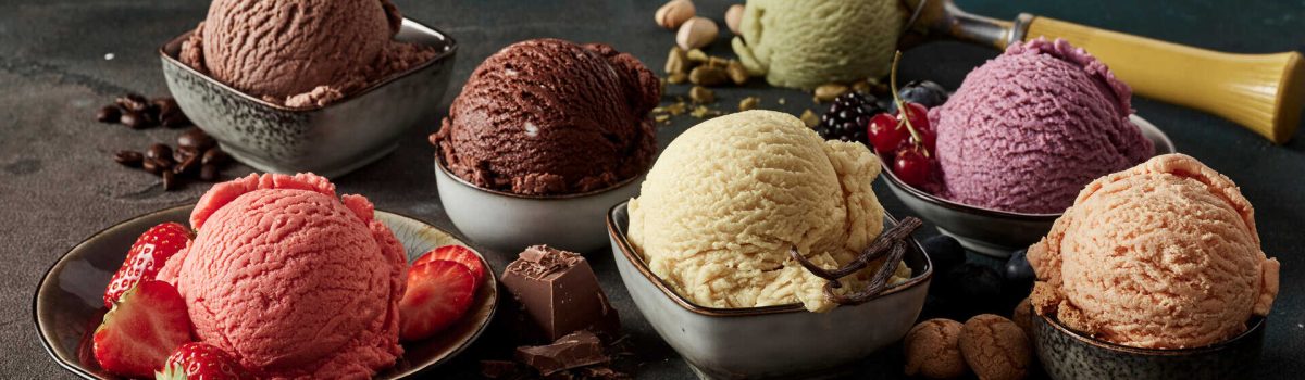 Gourmet summer dessert of artisanal or craft ice cream made with fresh berries, macaroons, coffee beans, pistachio nuts and chocolate served in bowls in a wide angle banner