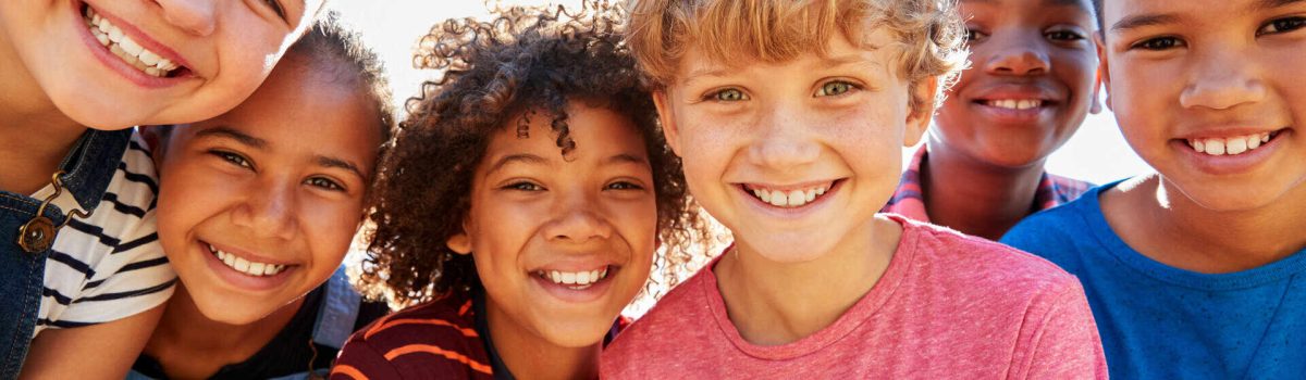 Close up of pre-teen friends in a park smiling to camera